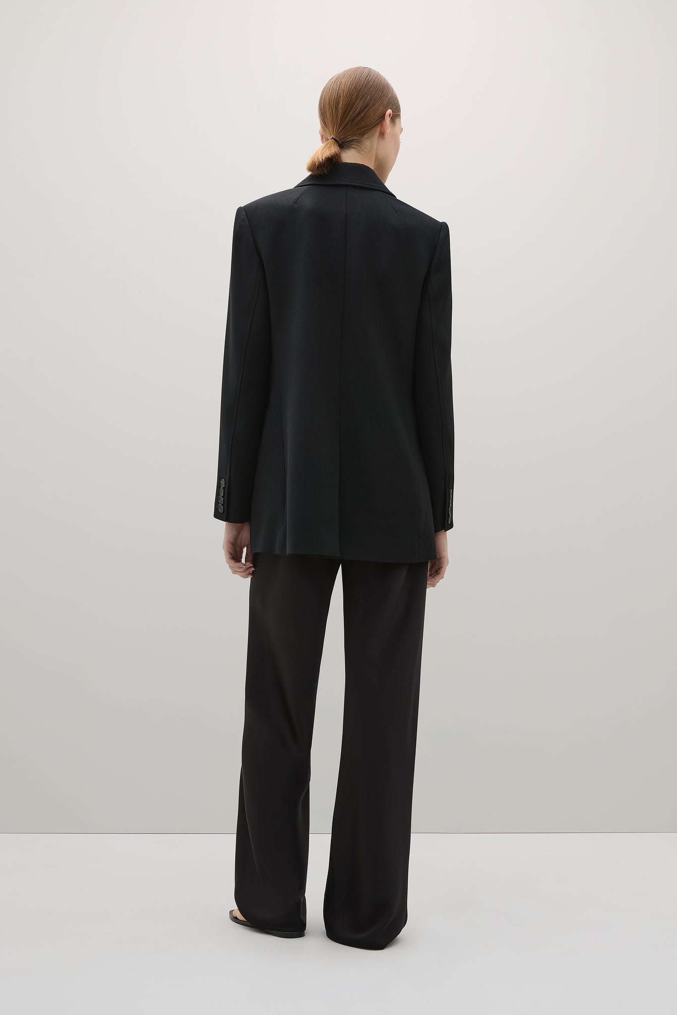 Person wearing a black suit on a white background