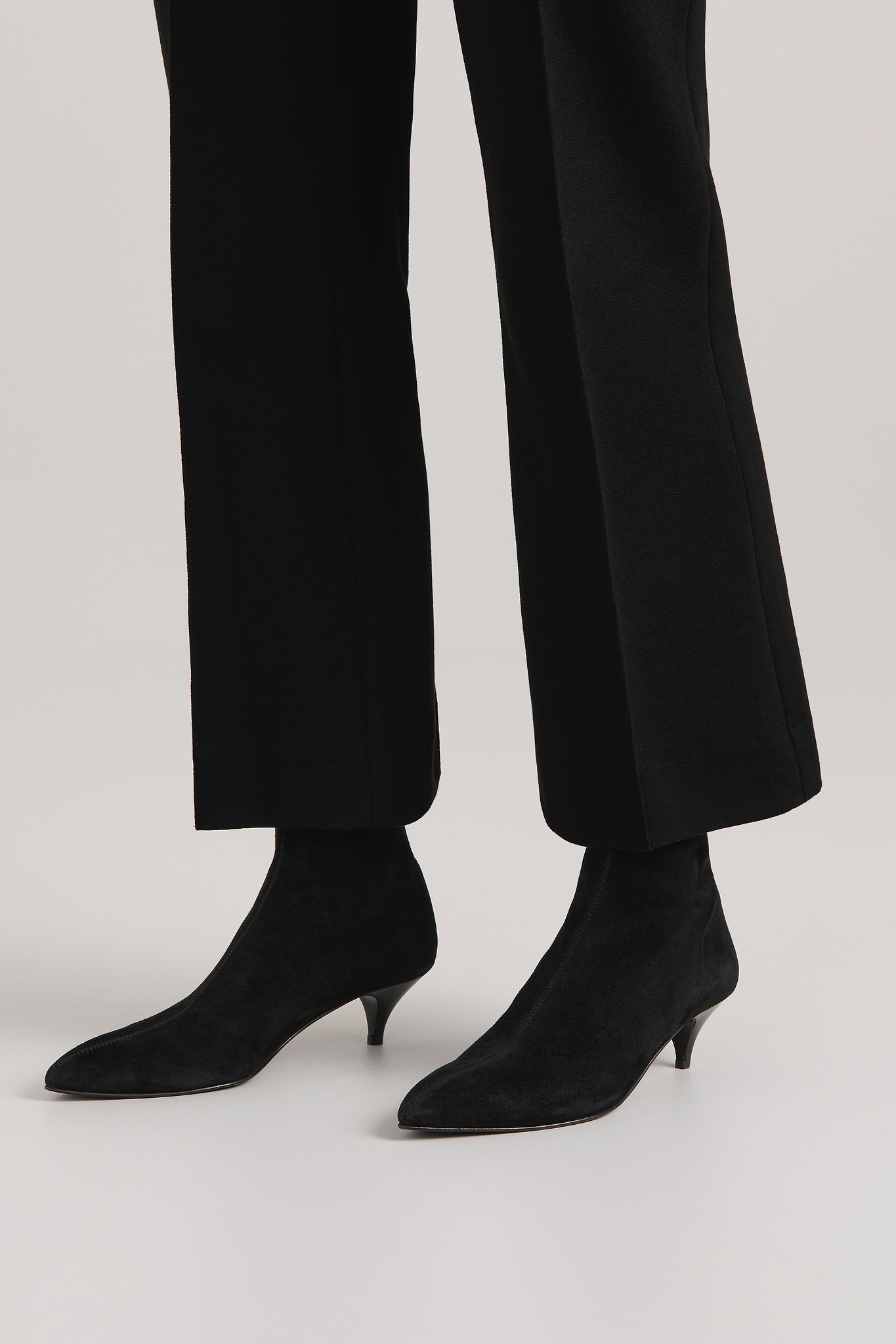 Black ankle boots worn with black pants on a light gray background
