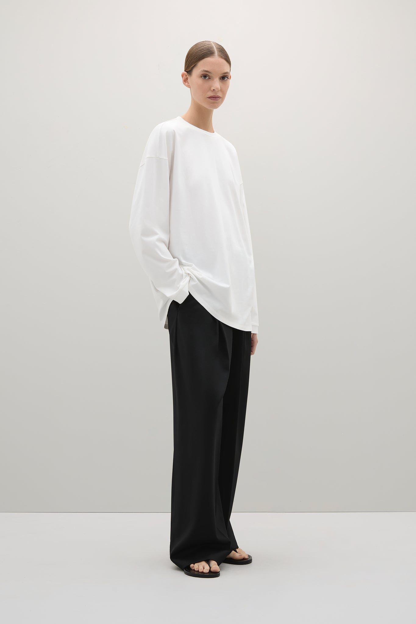 Woman wearing a white blouse and black pants on a plain background