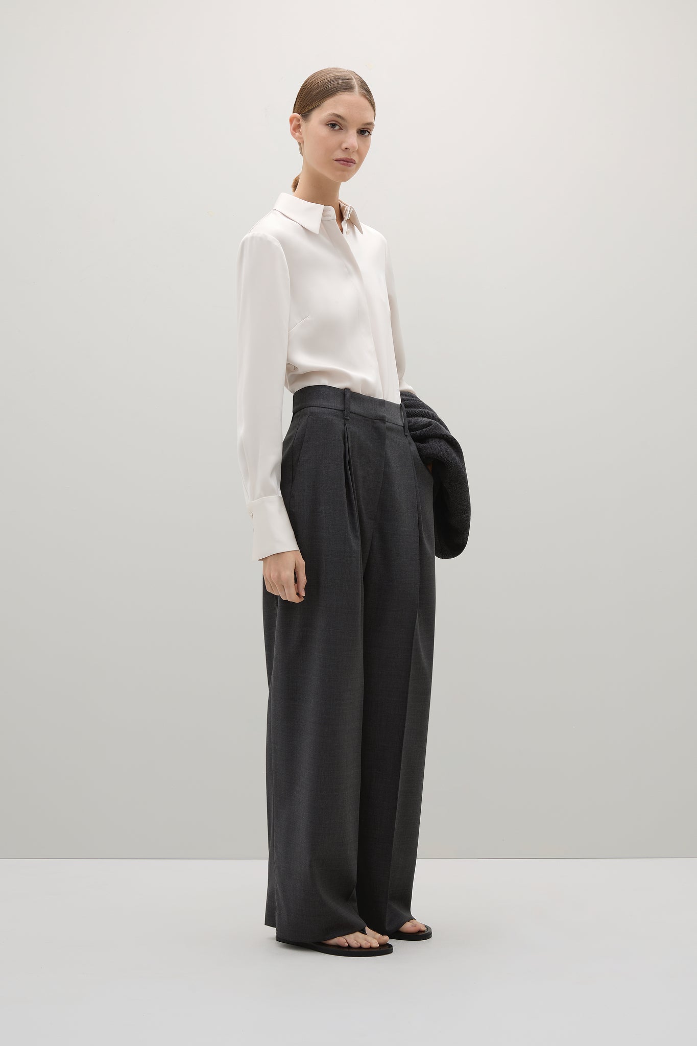 Woman wearing a white shirt and black pants on a plain background