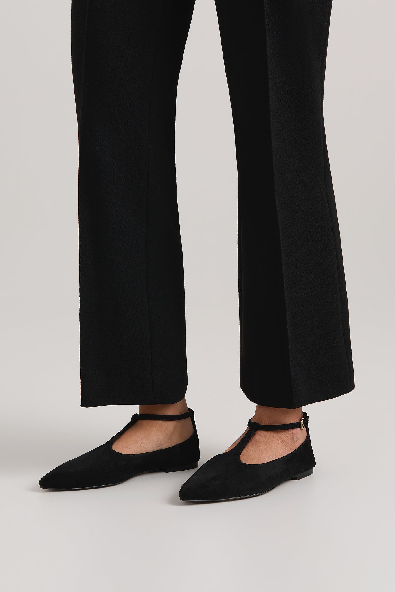 Black flats worn with black pants on a white background
