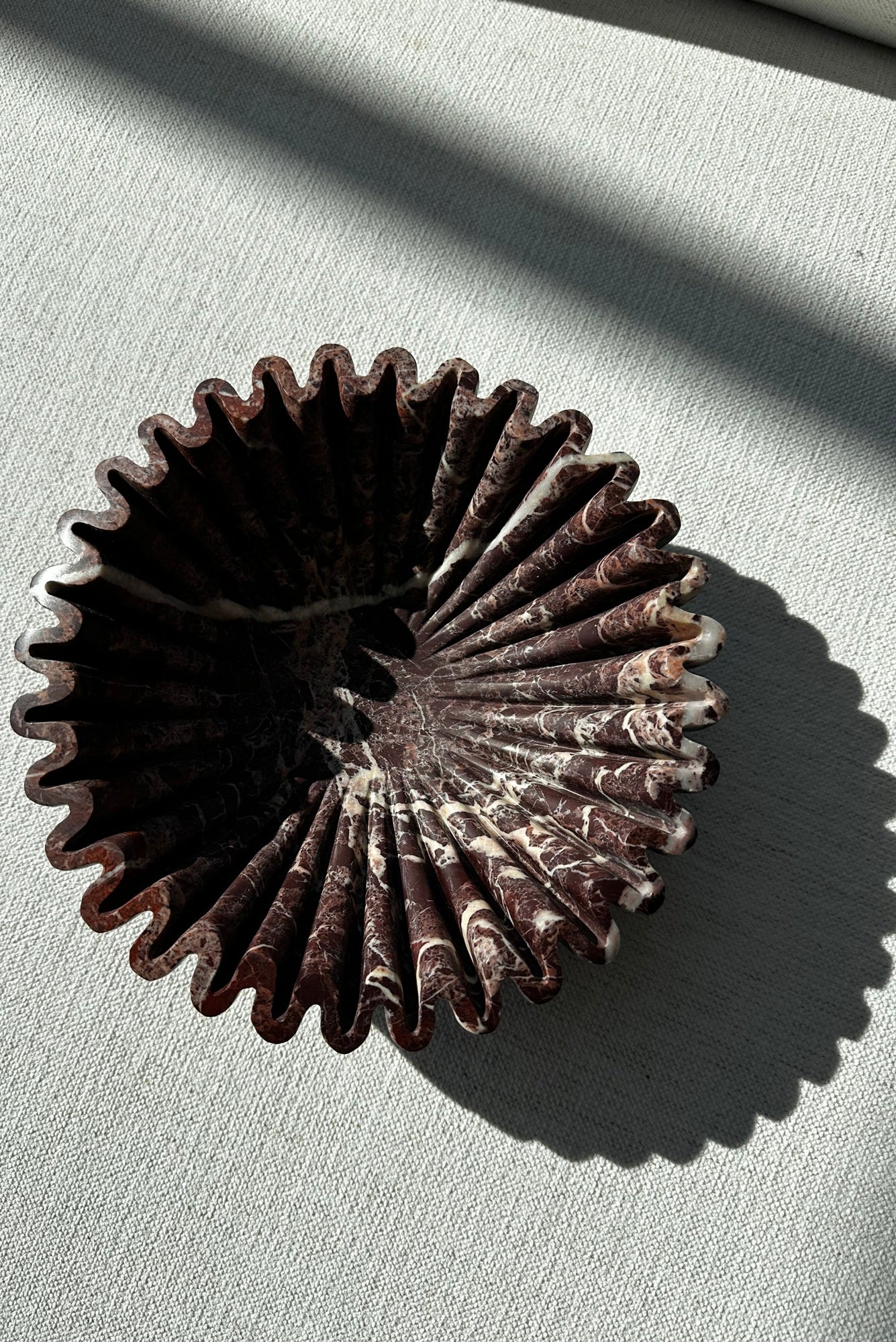 stone ruffle bowl in cherry gold on a light gray surface