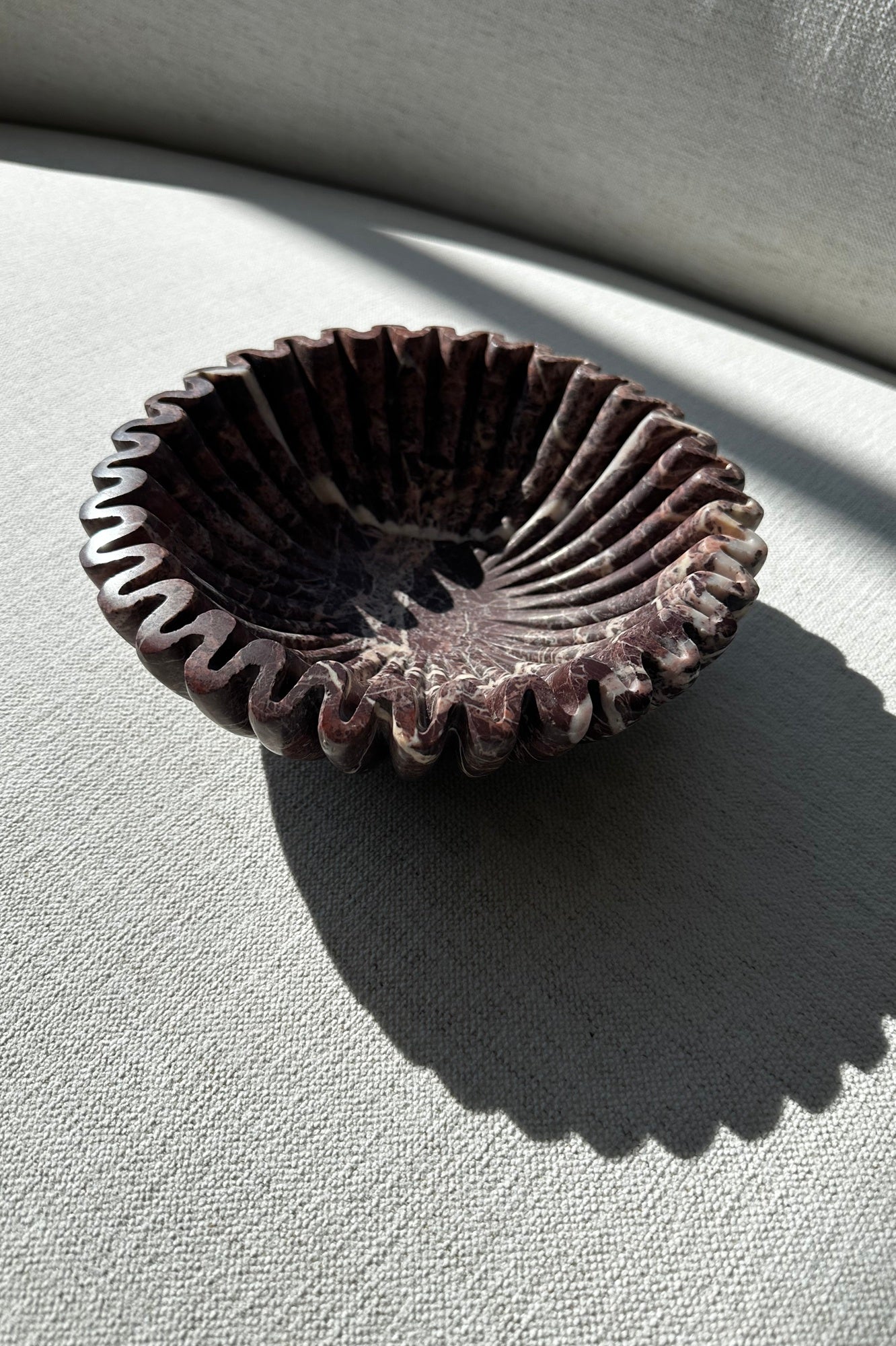 stone ruffle bowl in cherry gold on a light gray surface