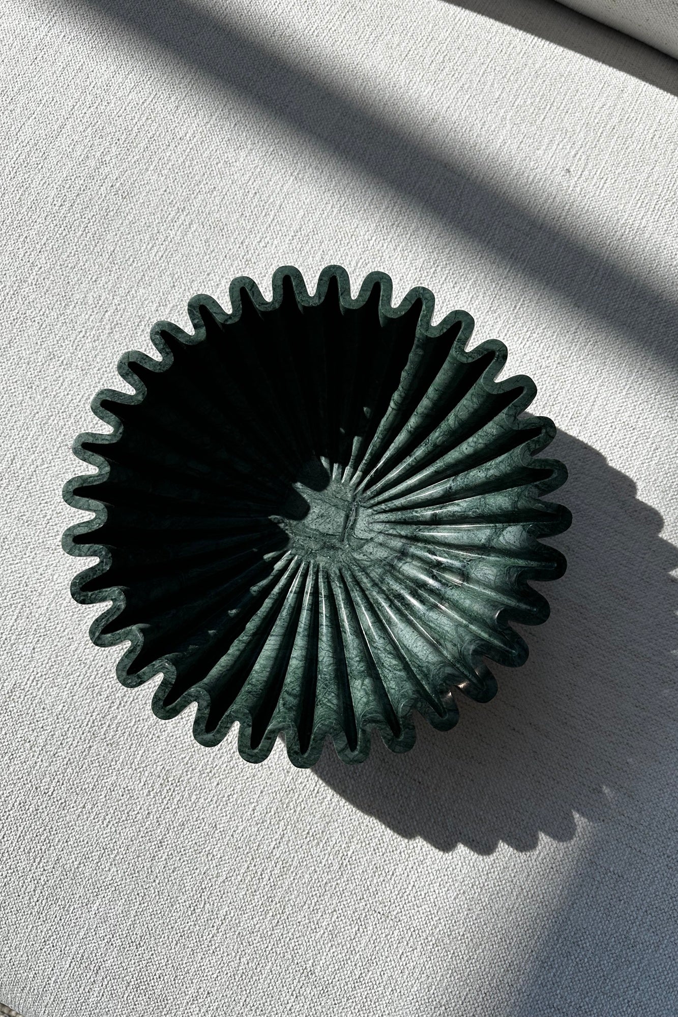 Emerald green stone decorative object with a textured surface on a light gray background