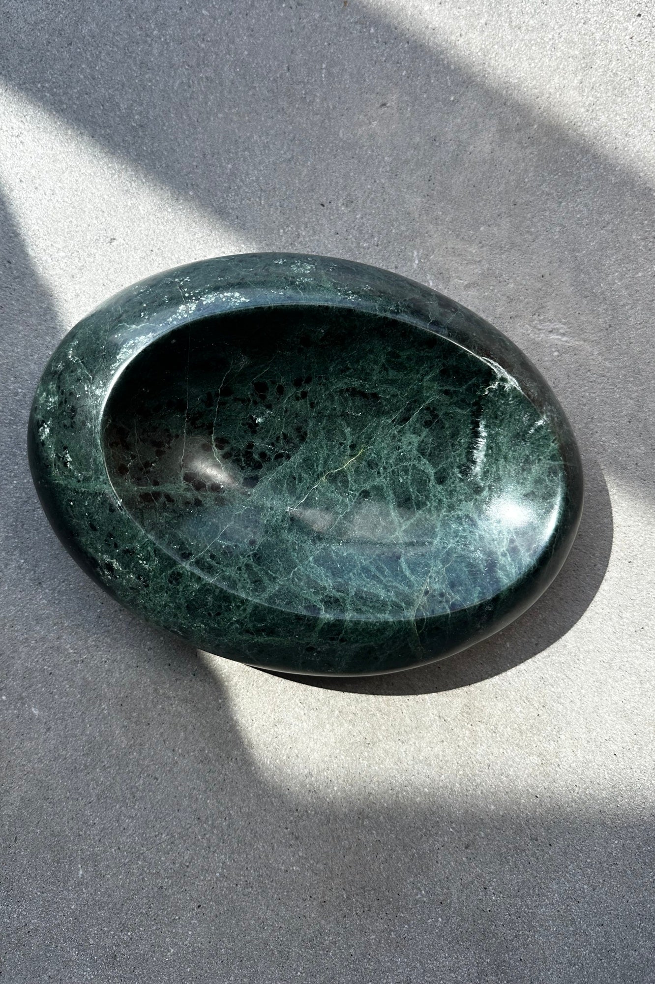 Emerald stone on a gray surface with shadows