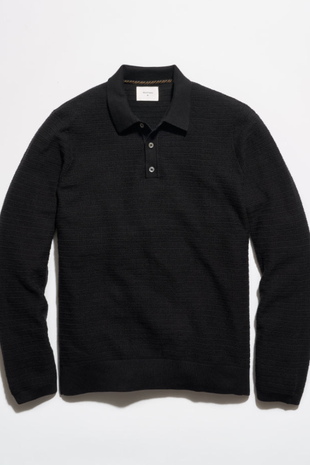 A black long-sleeve knit polo shirt with a textured waffle pattern, laid flat against a white background.