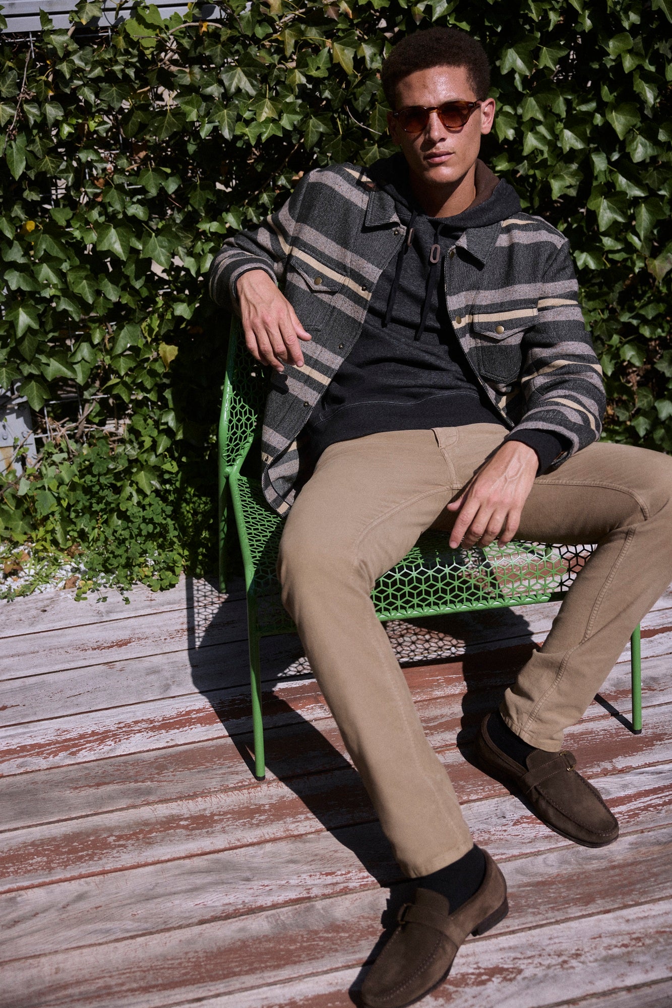 Man sitting on a green chair against a leafy background