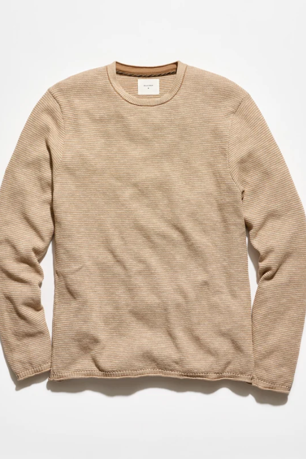 A beige long-sleeve crewneck knit sweater with a fine ribbed texture, laid flat against a clean white background.