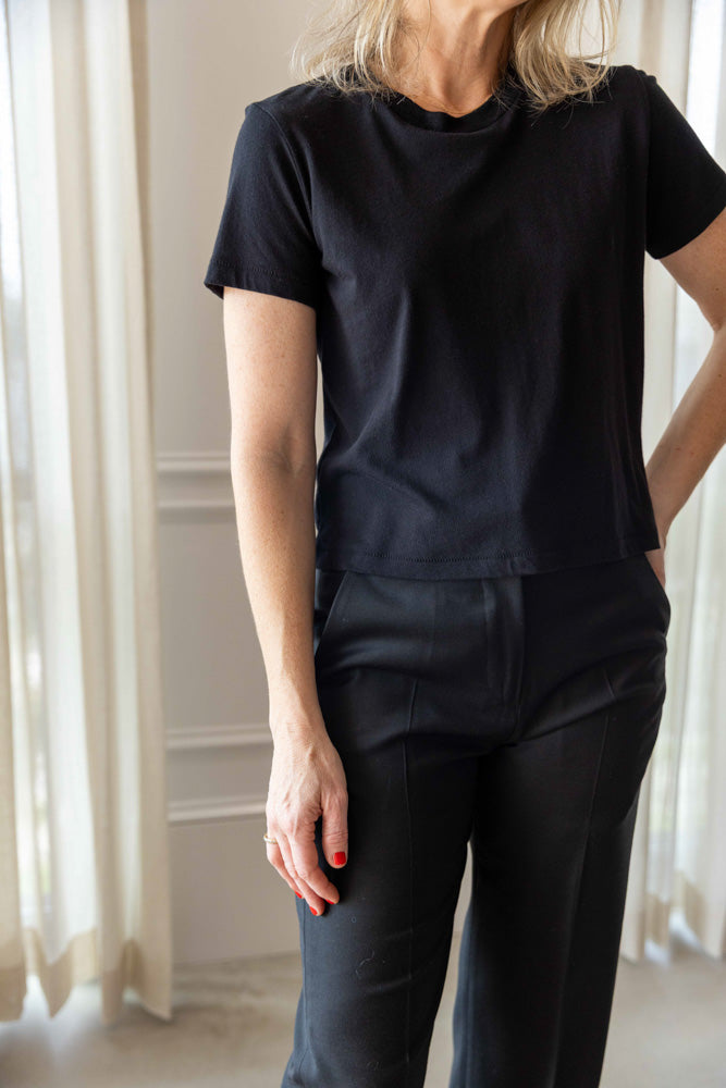 Eterne Short Sleeve Boxy Tee in black cotton modal, worn three-quarter view with black tailored trousers