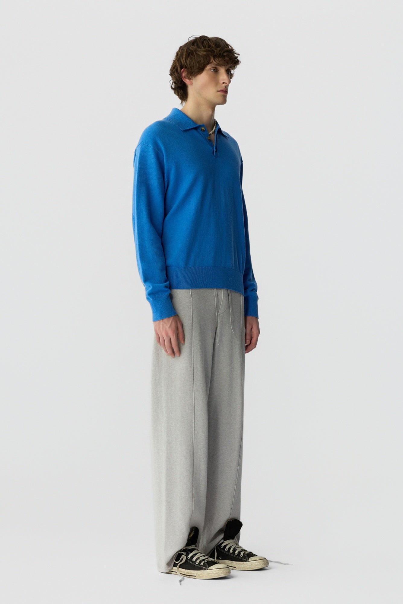 Person wearing a blue sweater and gray pants on a white background