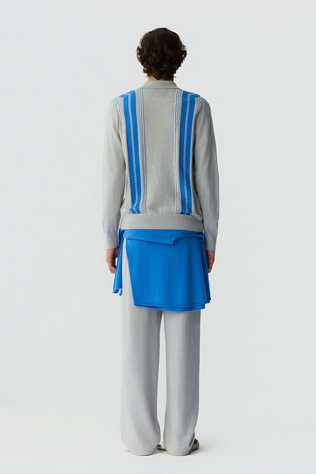 Person wearing a gray and blue outfit with wide-leg pants on a white background