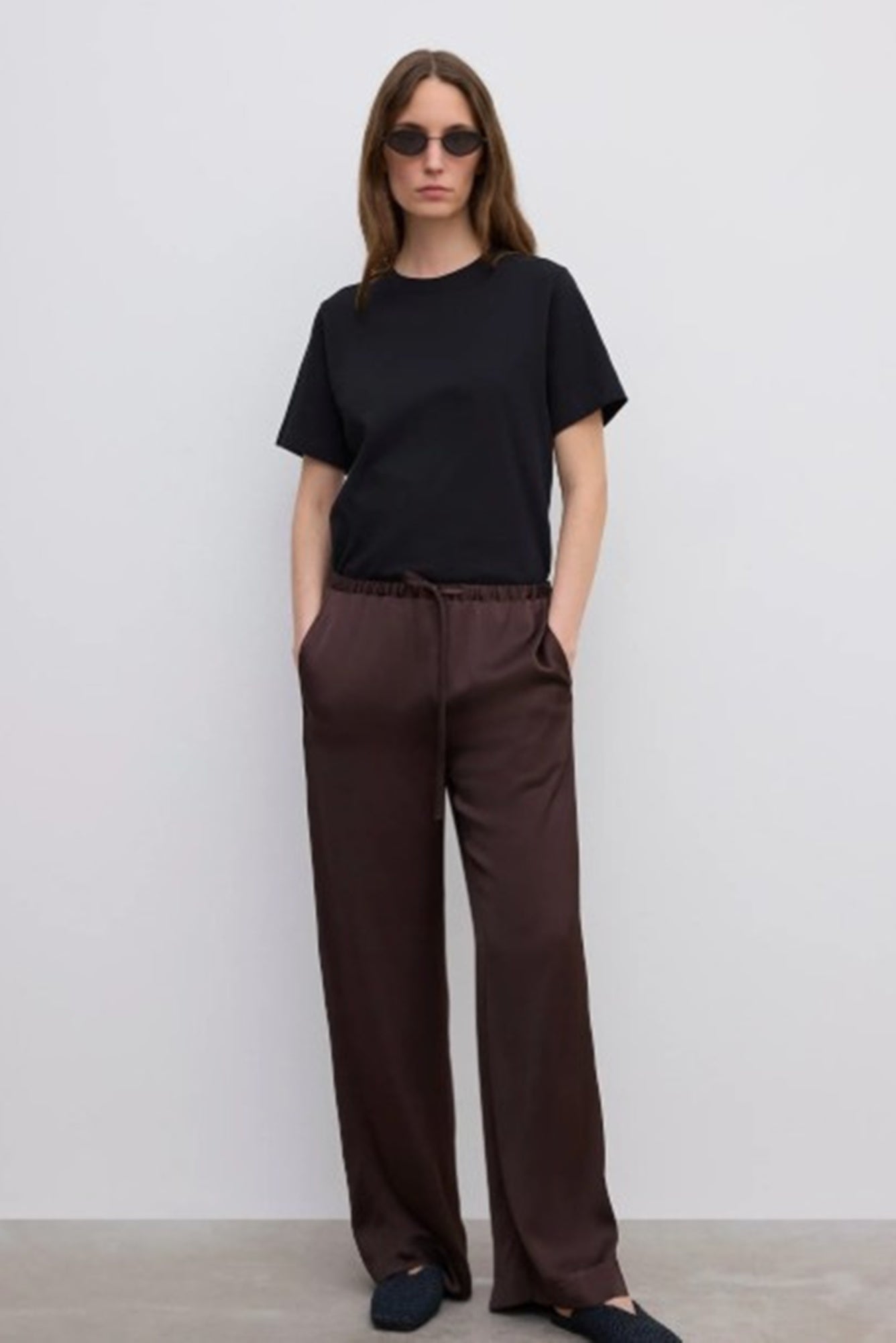 Person wearing a black t-shirt and brown pants against a white background