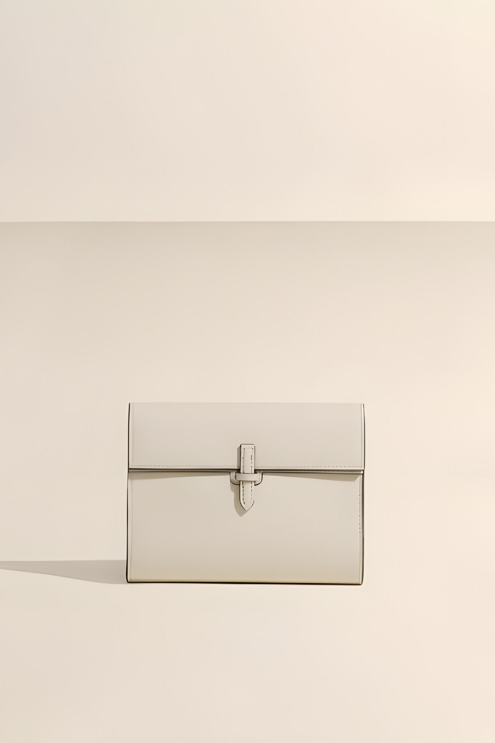 Rectangular clutch bag with a silver clasp on a beige background