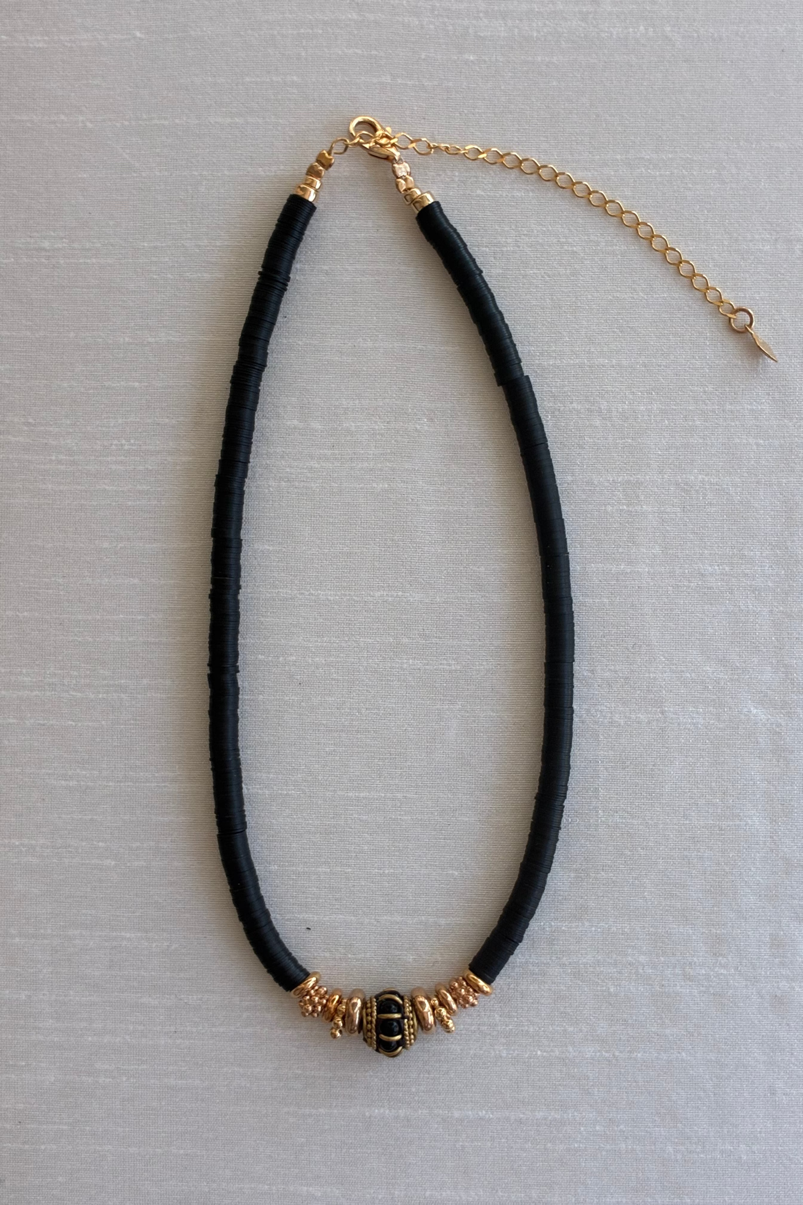 Gachon Pothier Puka Bakelite beaded necklace with black beads and 18kt gold plated hardware on a light gray background.