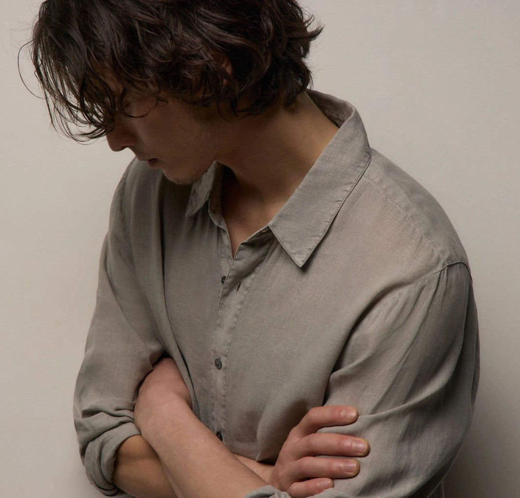 Person wearing a light gray shirt against a plain background