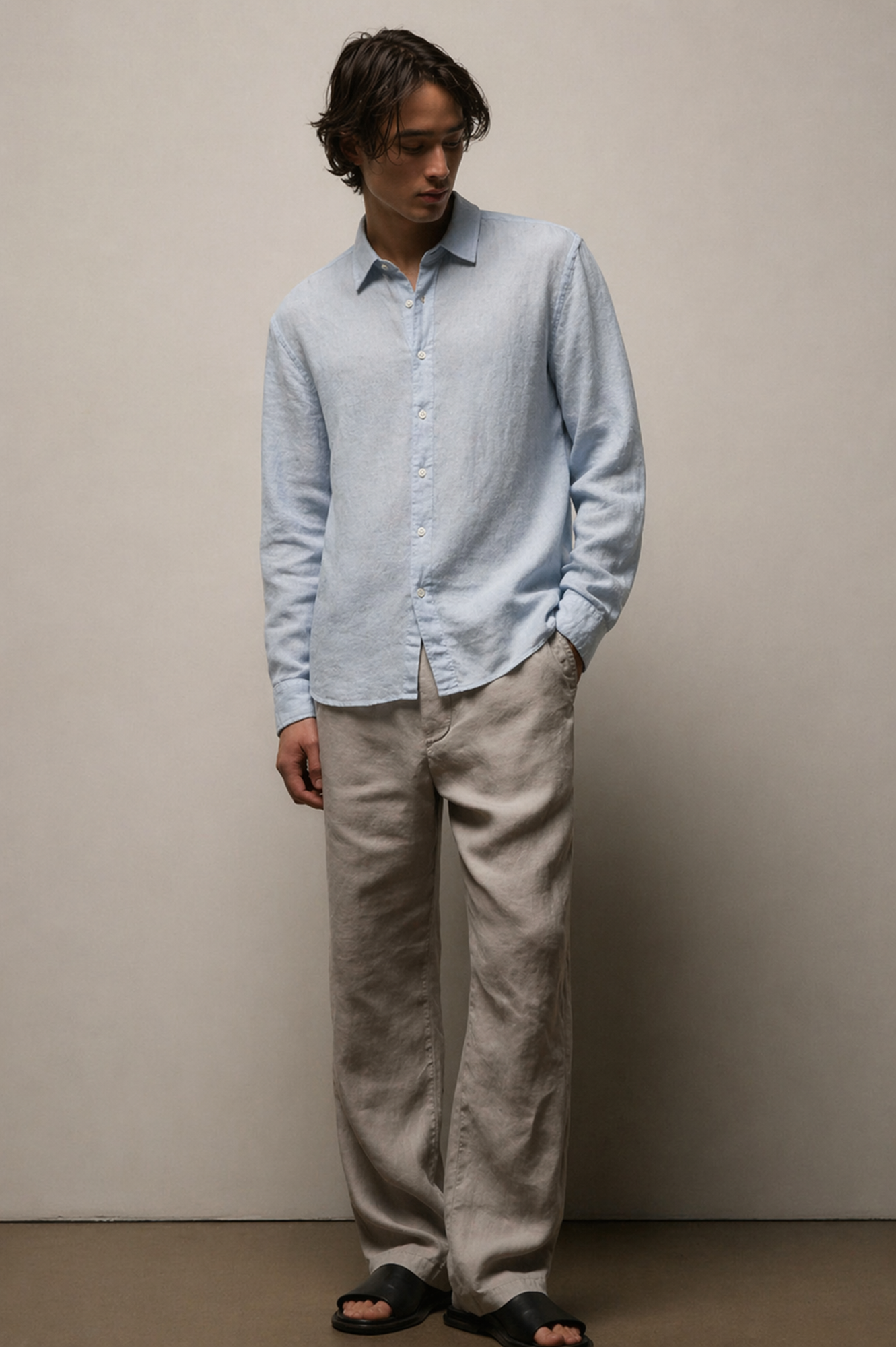 Man wearing a light blue shirt and beige pants against a plain background