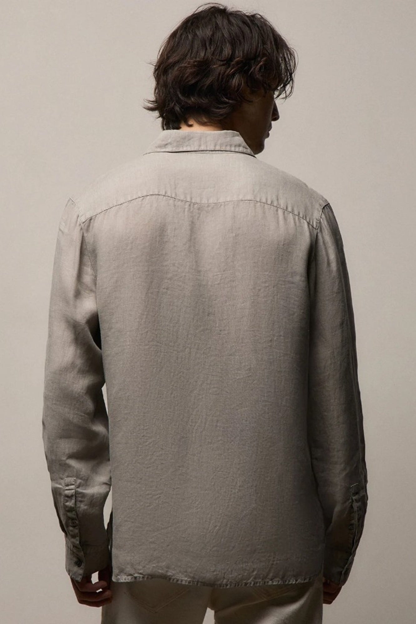 Person wearing a gray shirt against a plain background