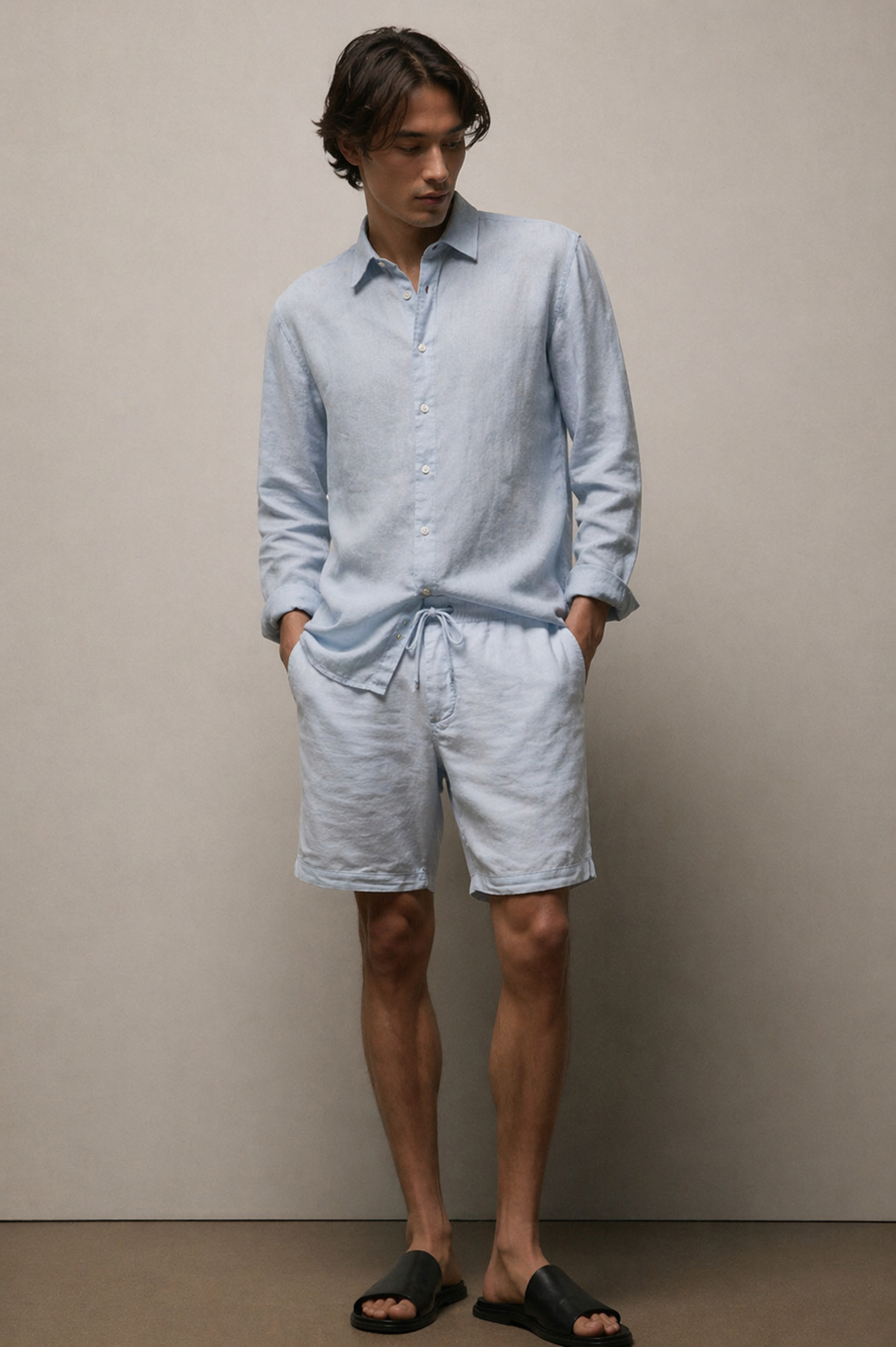 Man wearing a light blue shirt and shorts against a plain background