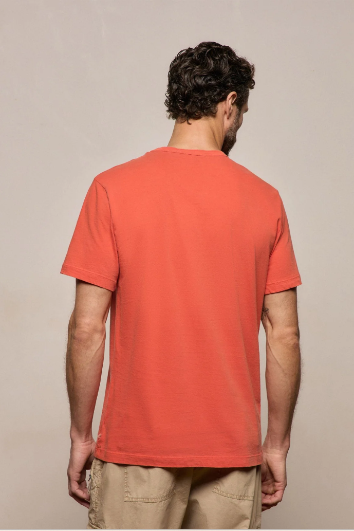 Man wearing an orange t-shirt against a beige background