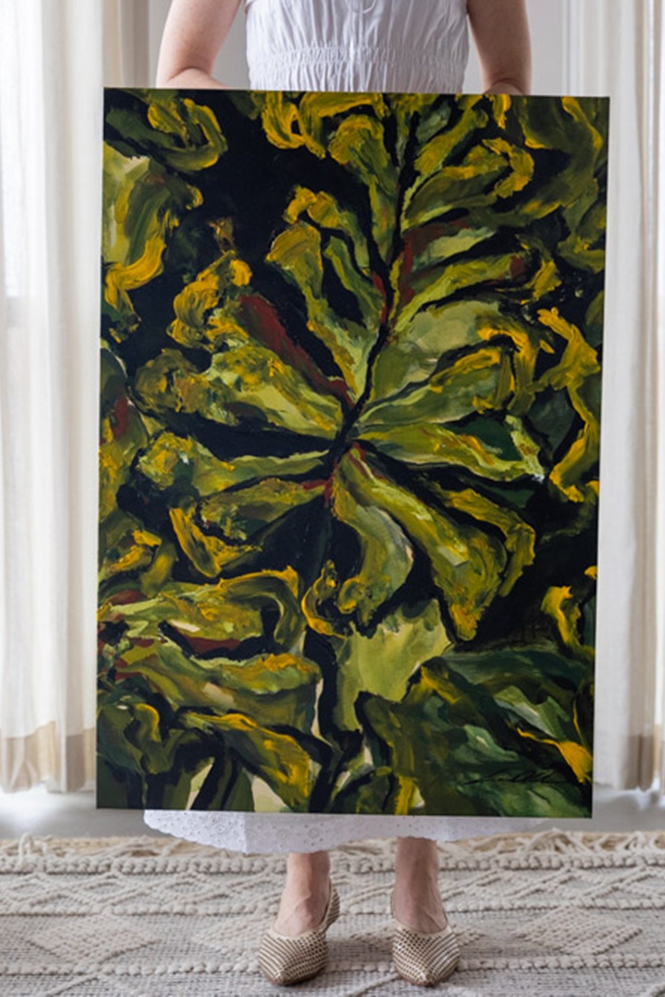 Person holding a large abstract painting with green and yellow leaves.