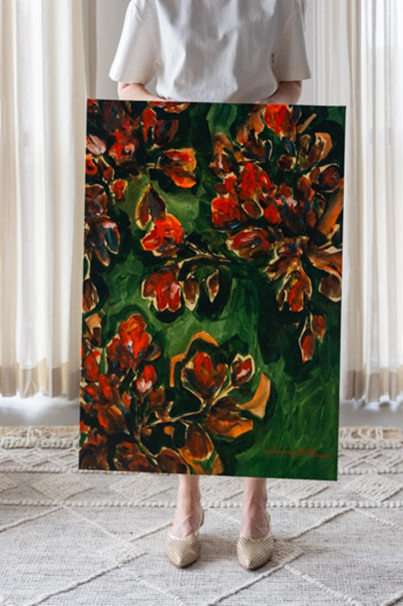 Person holding a painting of red flowers on a green background