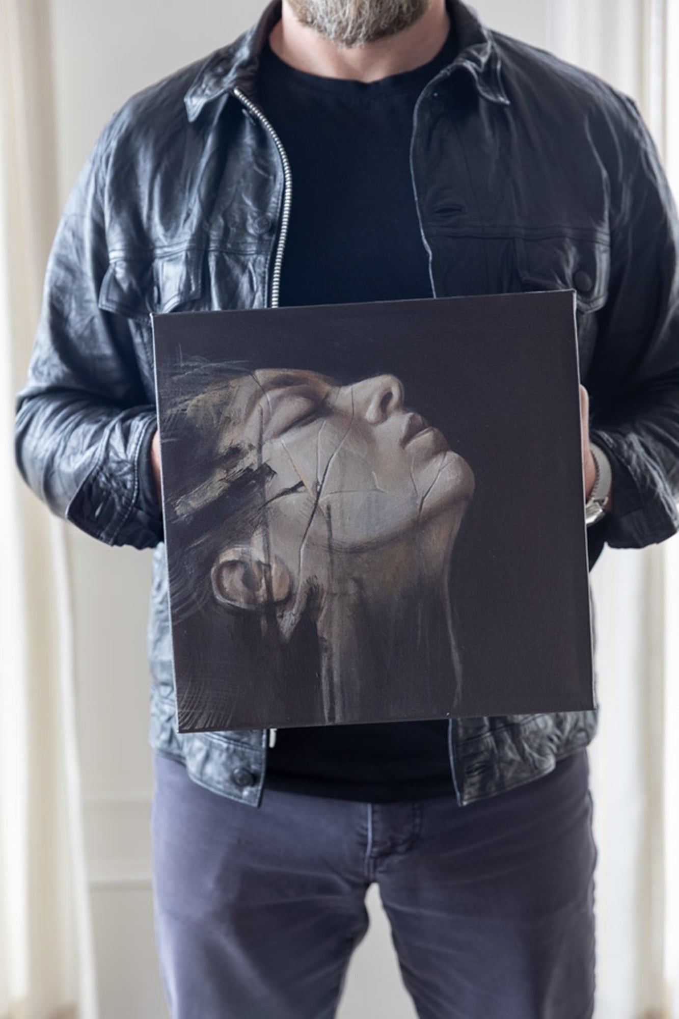 Person holding a black square with a stylized face drawing on it