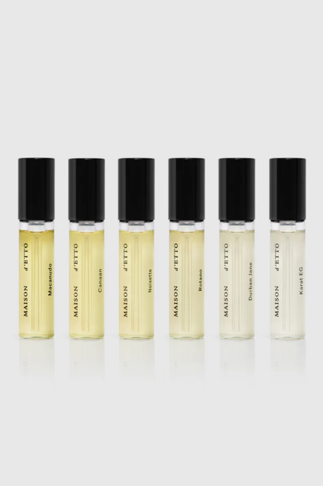 Set of six perfume bottles with black caps on a light gray background