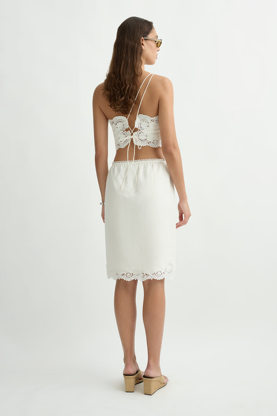 Backside of a woman wearing the posse darya top standing in front of a cream background