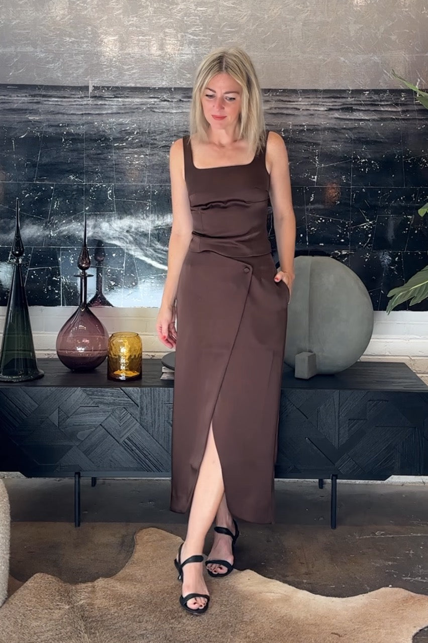 Woman in a brown dress standing in a room with decorative elements.