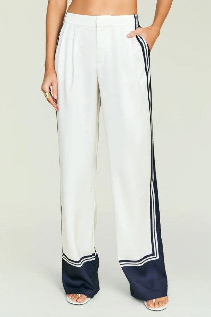 Woman wearing seroya marlowe satin pants standing in front of a cream background