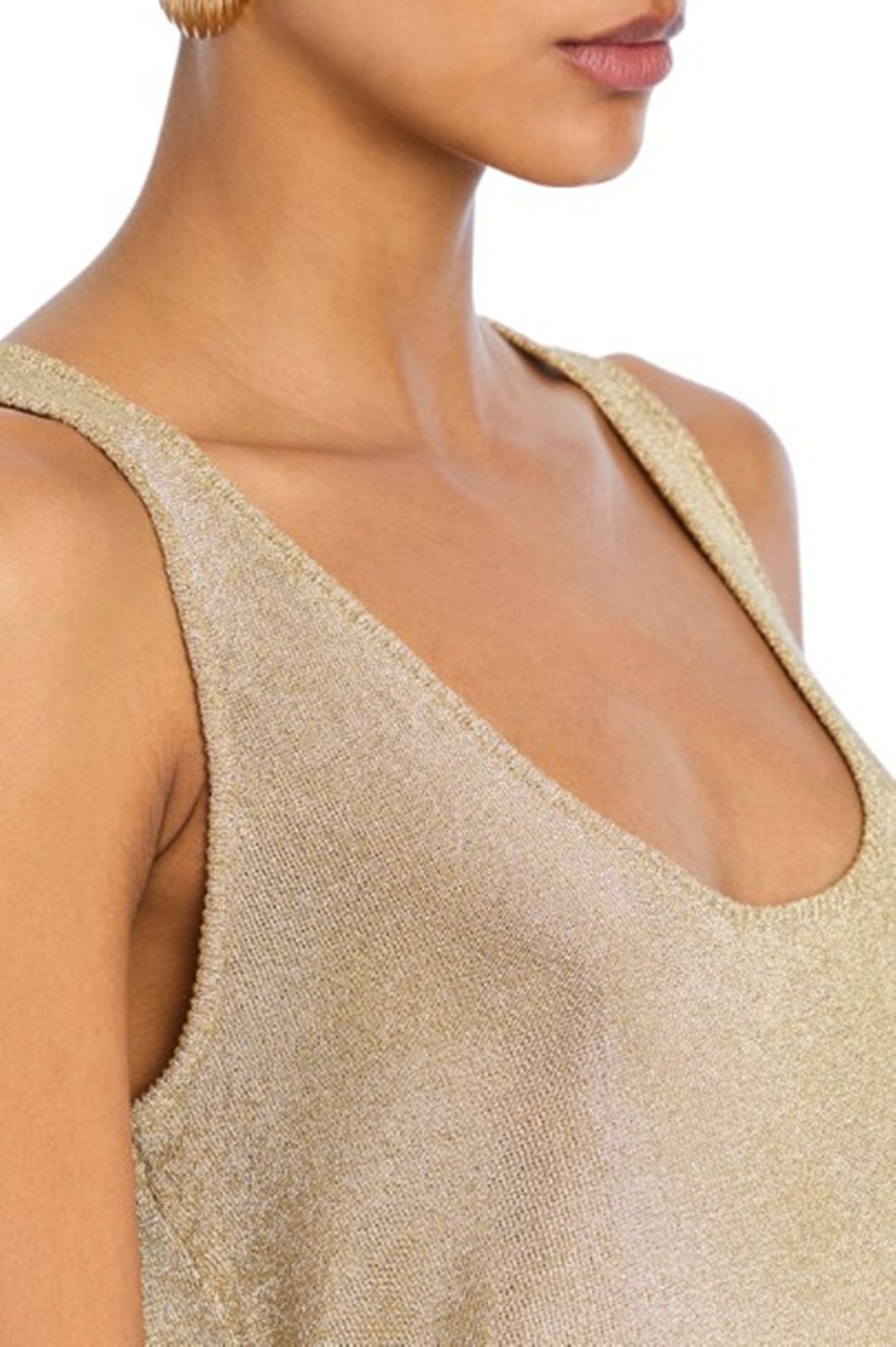 Close-up of a person wearing a sparkly gold dress with a plain background