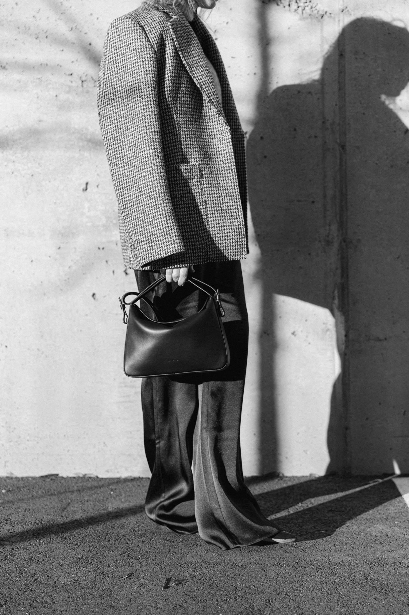 image of a woman wearing the House of Dagmar Tweed Coat, Seroya Viva Satin Pants and Aesther Ekme Handbag
