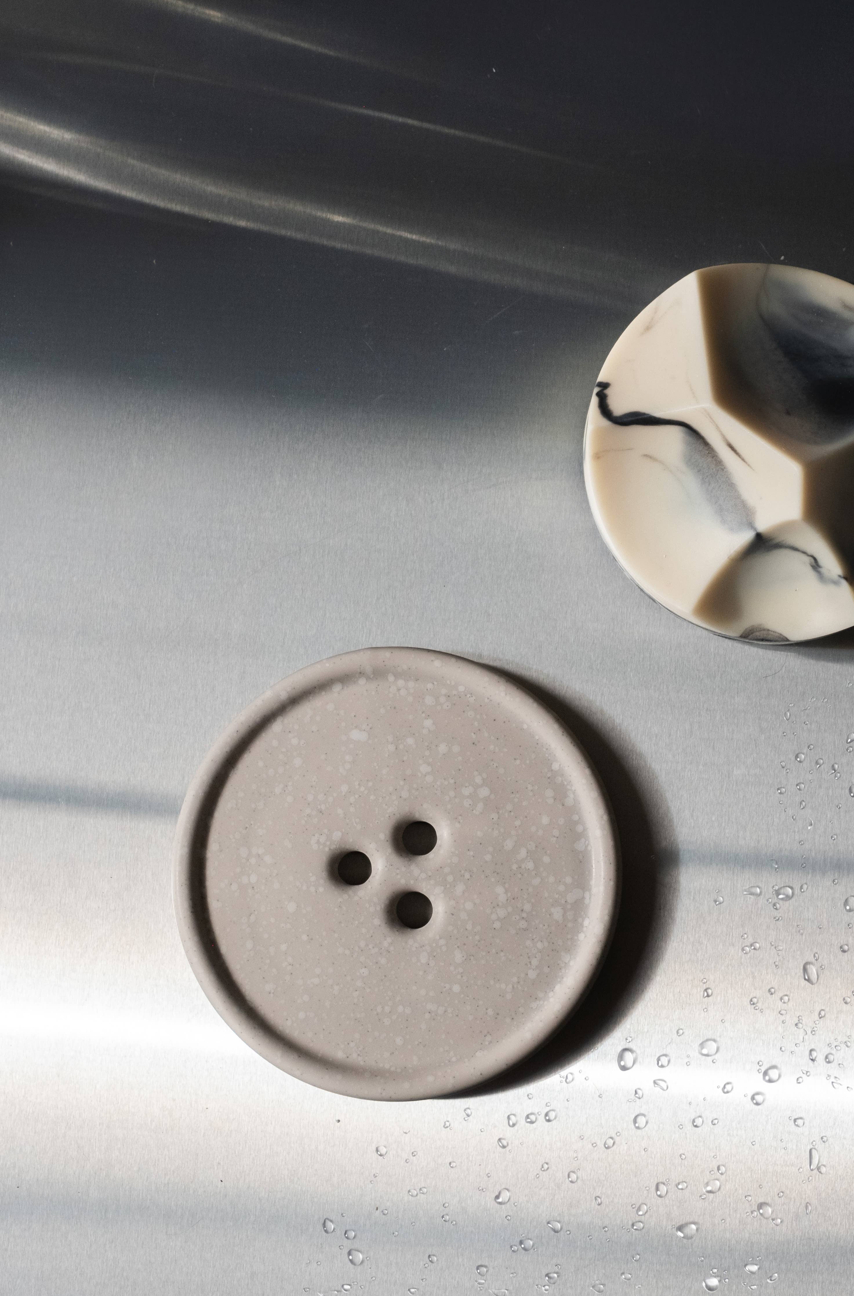 Two ceramic buttons on a reflective surface with a dark background