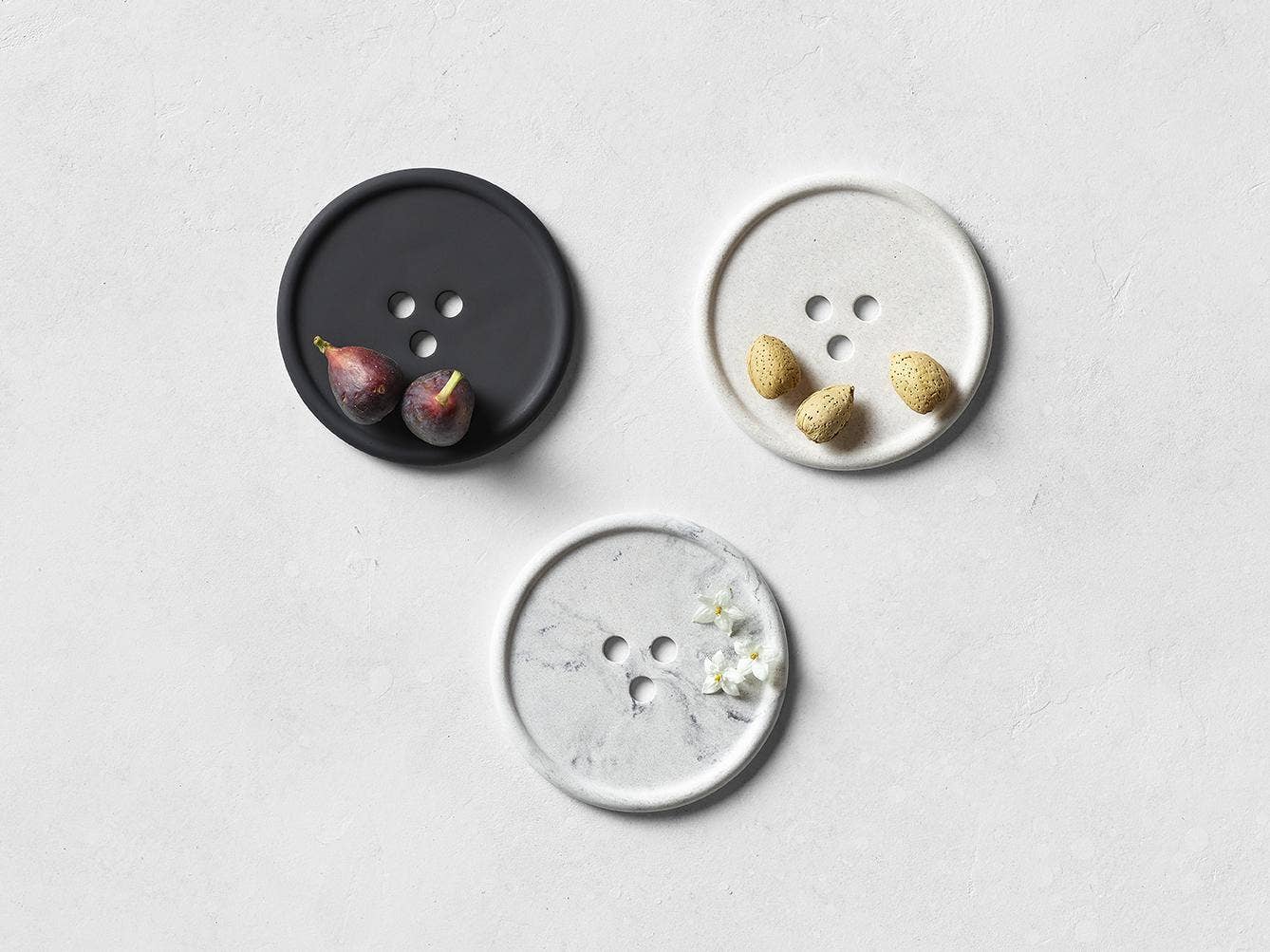 Three decorative buttons with small items on a light gray surface