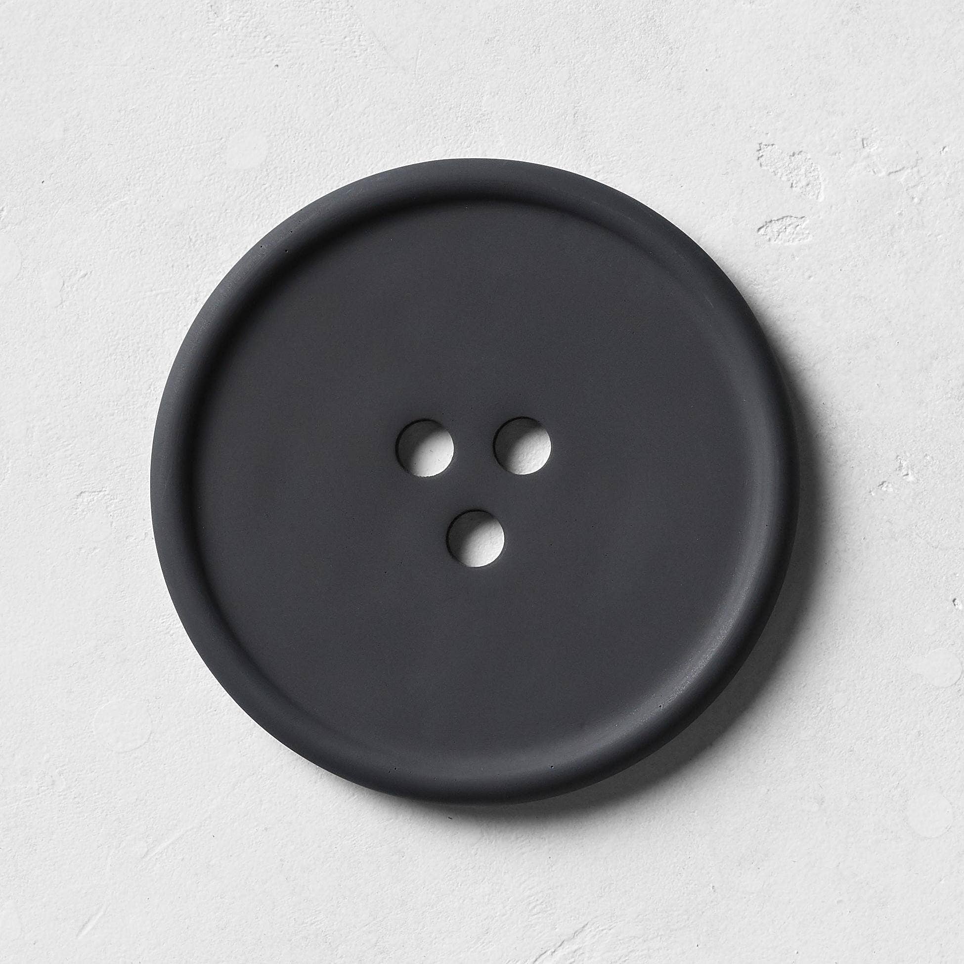 Black button with four holes on a light gray background