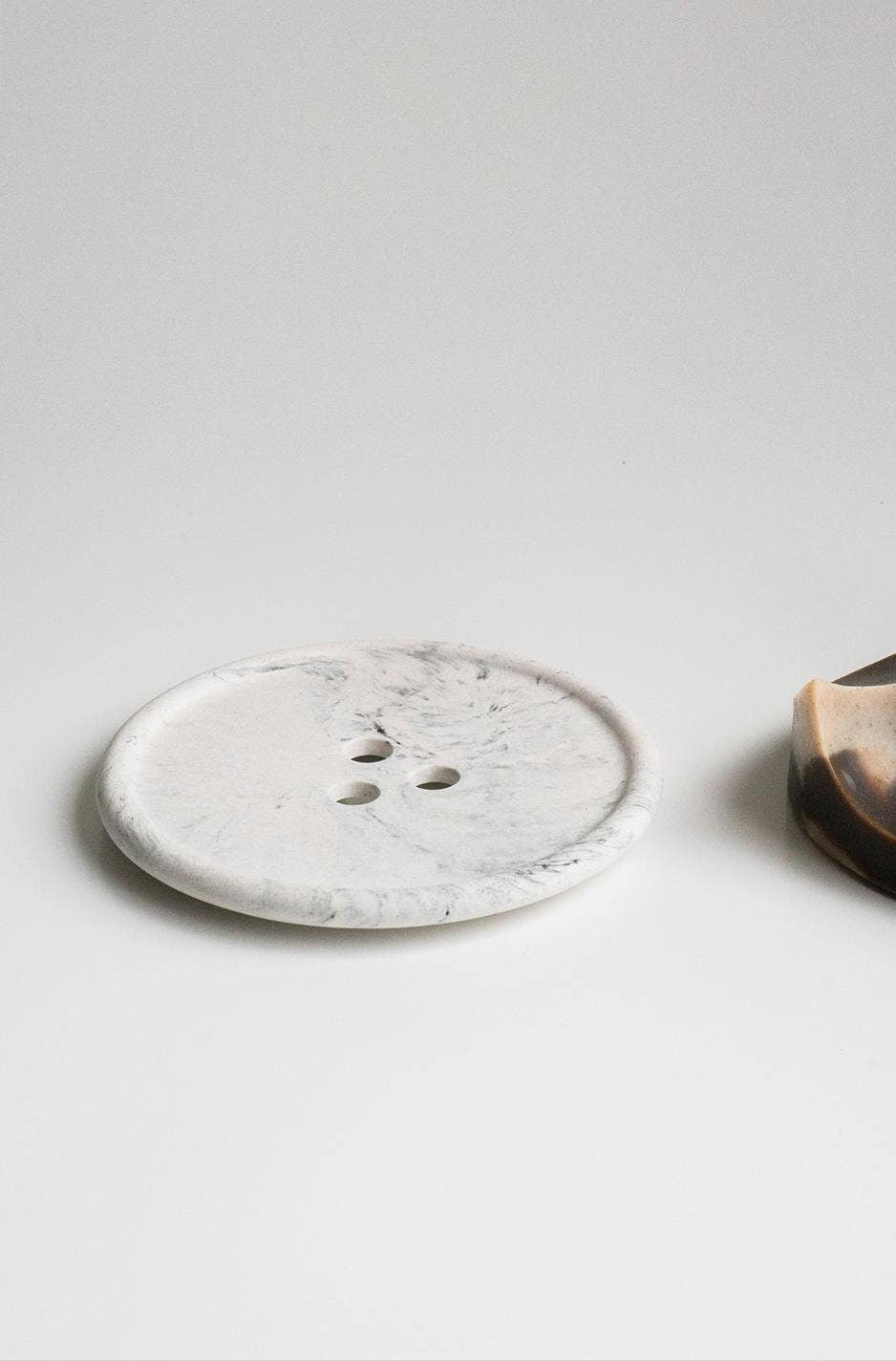 Two ceramic items, one round and one half-moon shape, on a light gray background