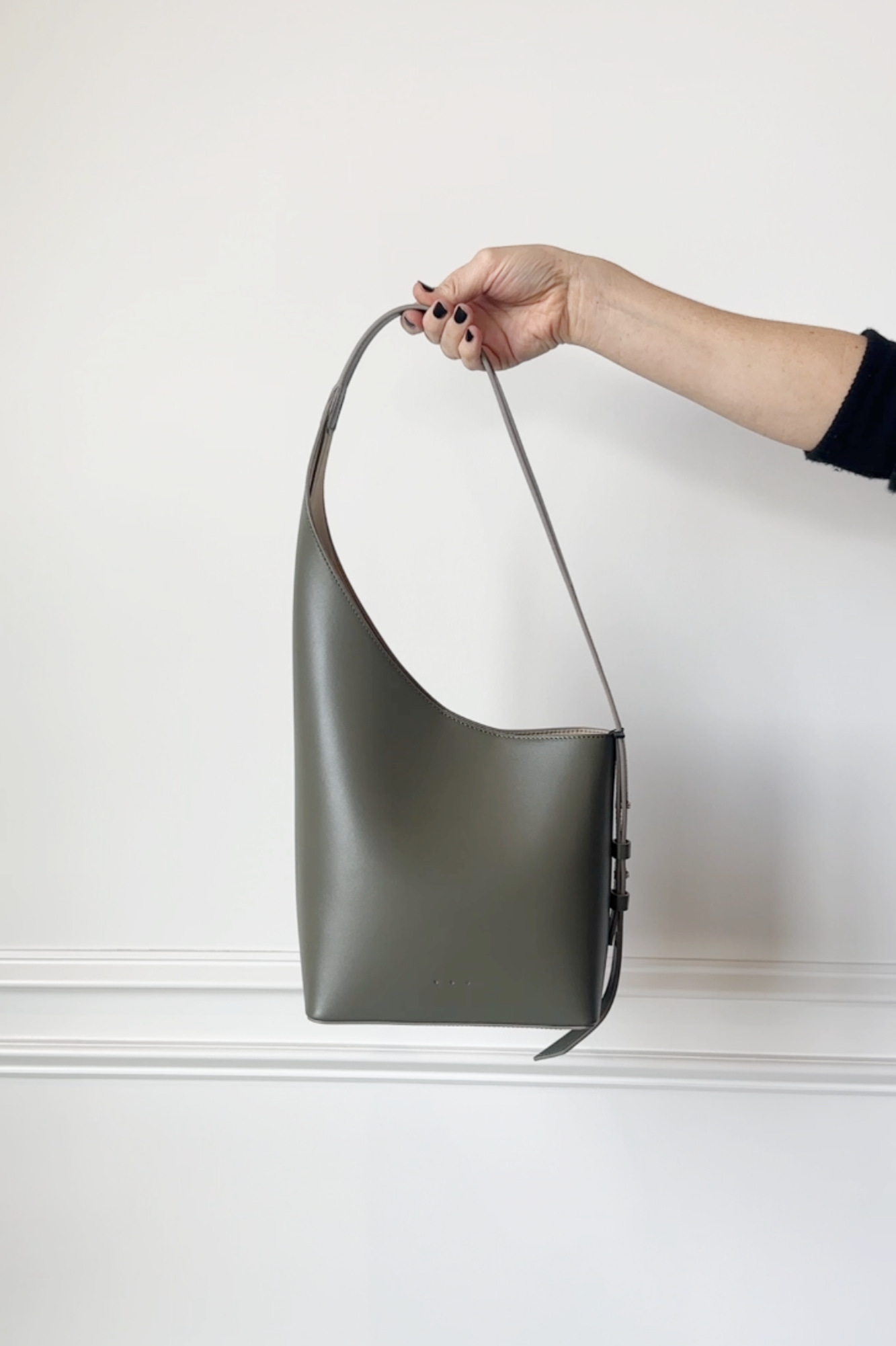 Hand holding a green leather bag against a white background