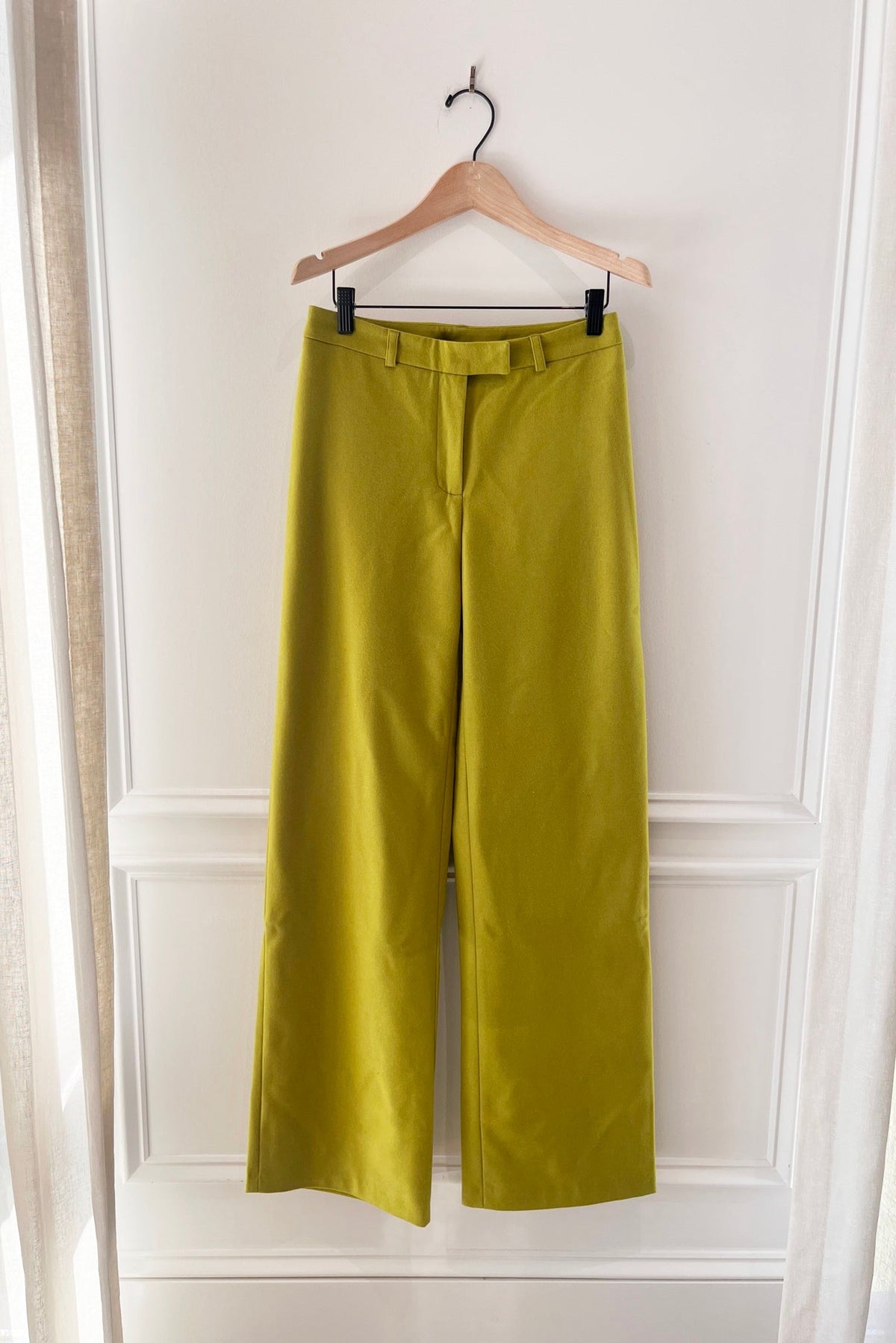 Alfie Straight Pant in Lime, high-waisted straight-leg trousers in chartreuse on a hanger against a white paneled wall