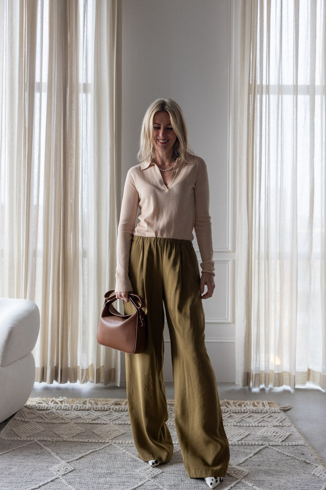 image of a woman wearing the Alysi Maglia Polo and Wide Leg Pull on Trouses with the Aesther Ekme Soft Baguette Bag