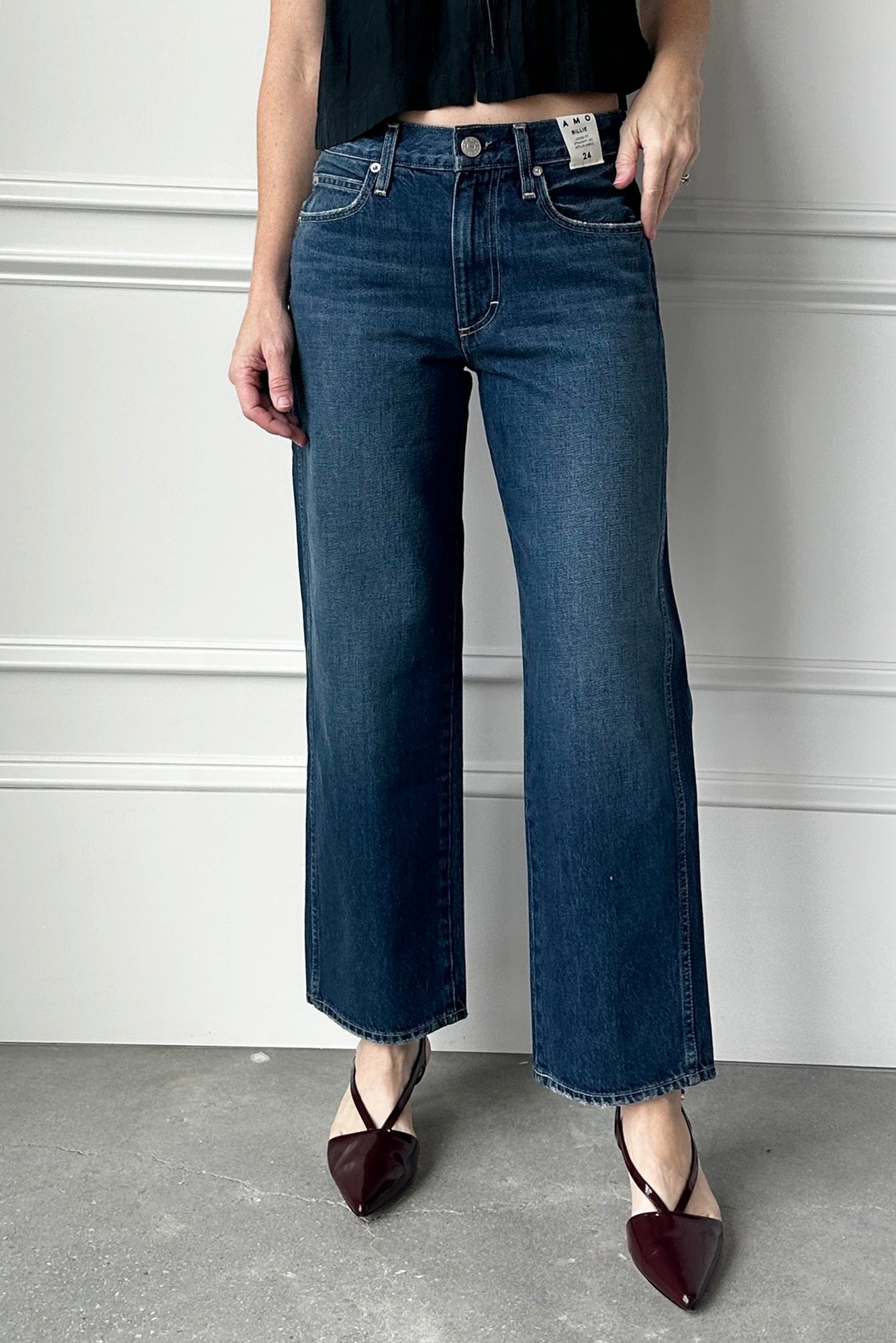 Person wearing blue jeans and black shoes against a plain background