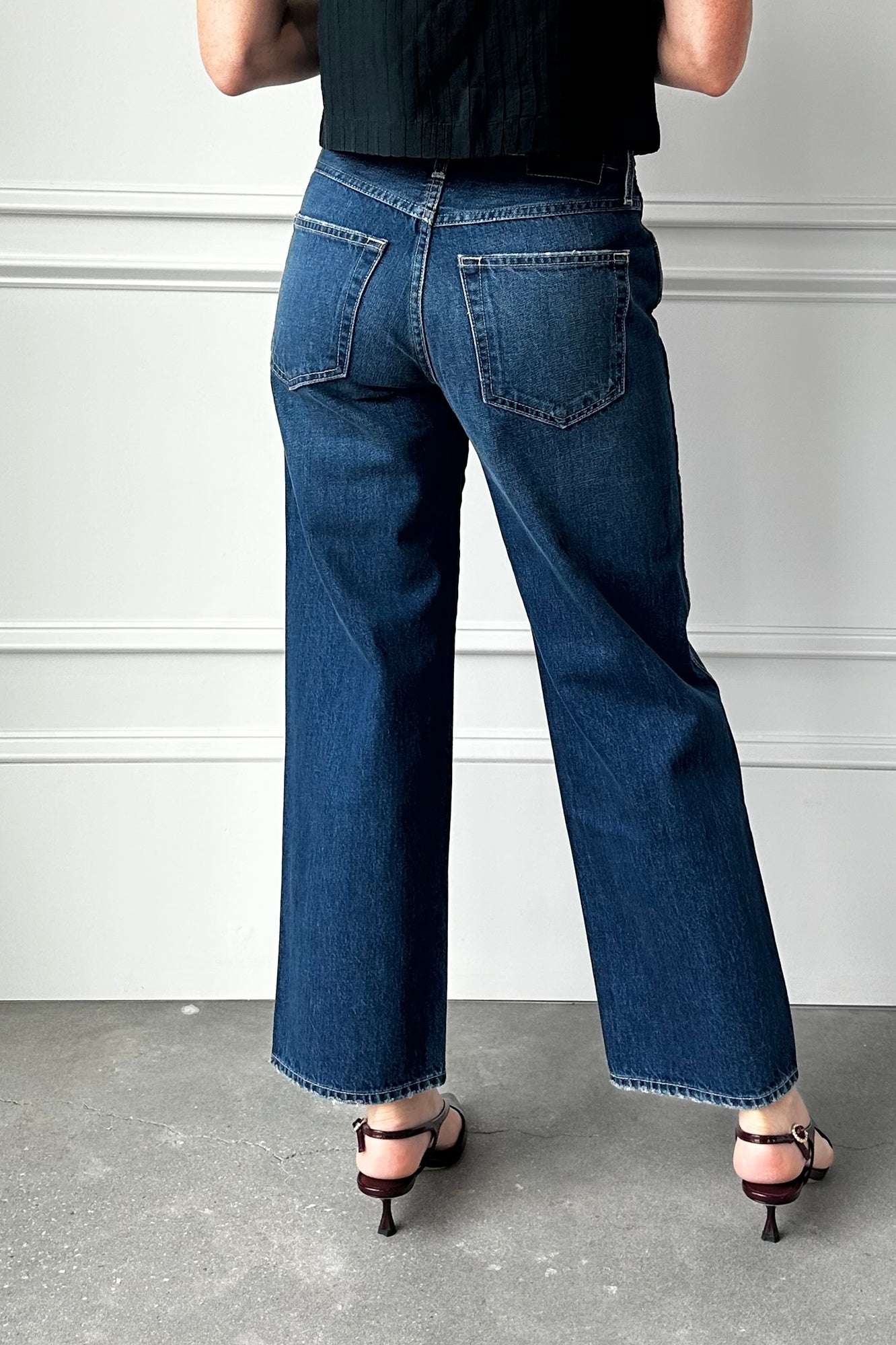 Person wearing blue jeans from behind on a plain background