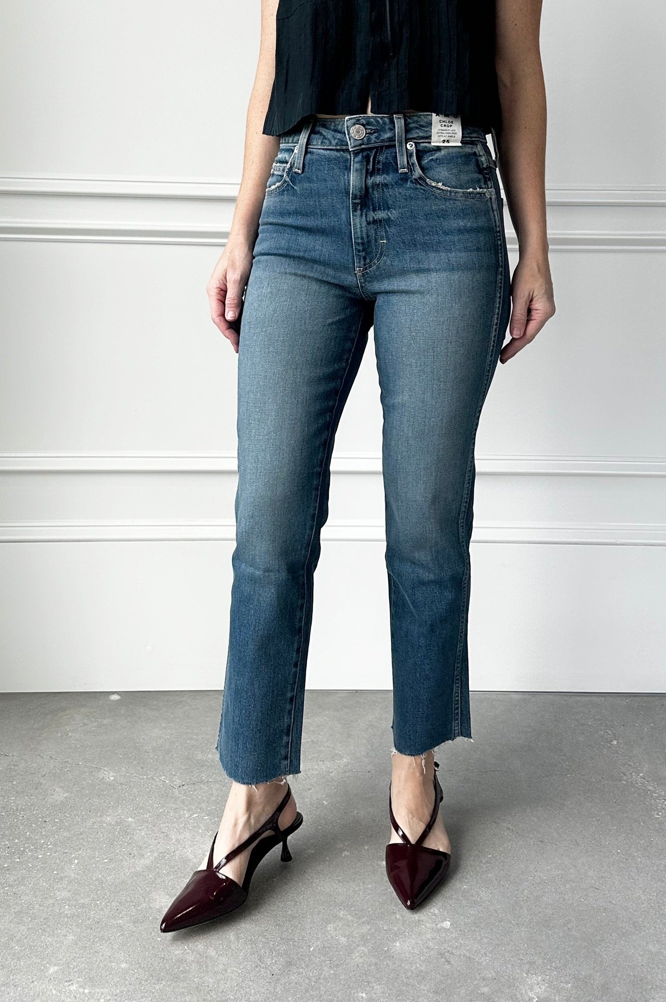 Person wearing blue jeans and black shoes on a plain background