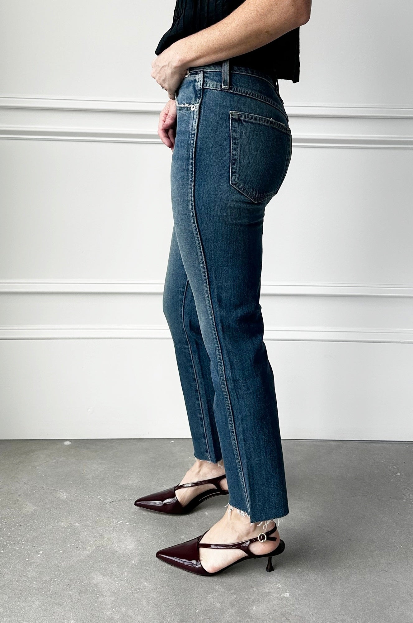 Person wearing blue jeans and black shoes on a plain background