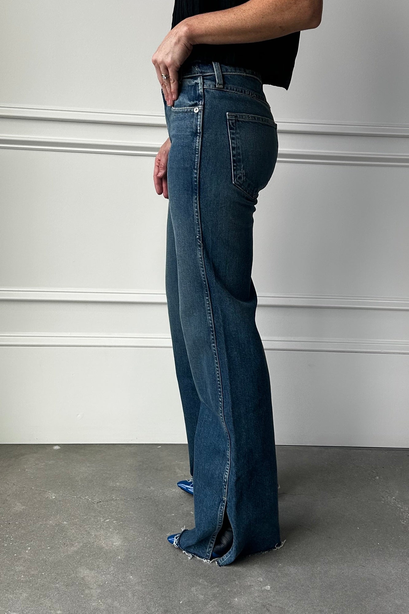 Person wearing blue jeans with a plain background