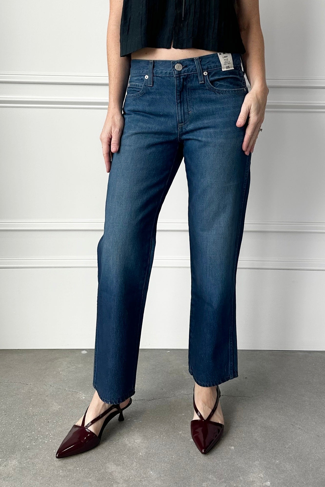 Person wearing blue jeans and dark shoes on a plain background