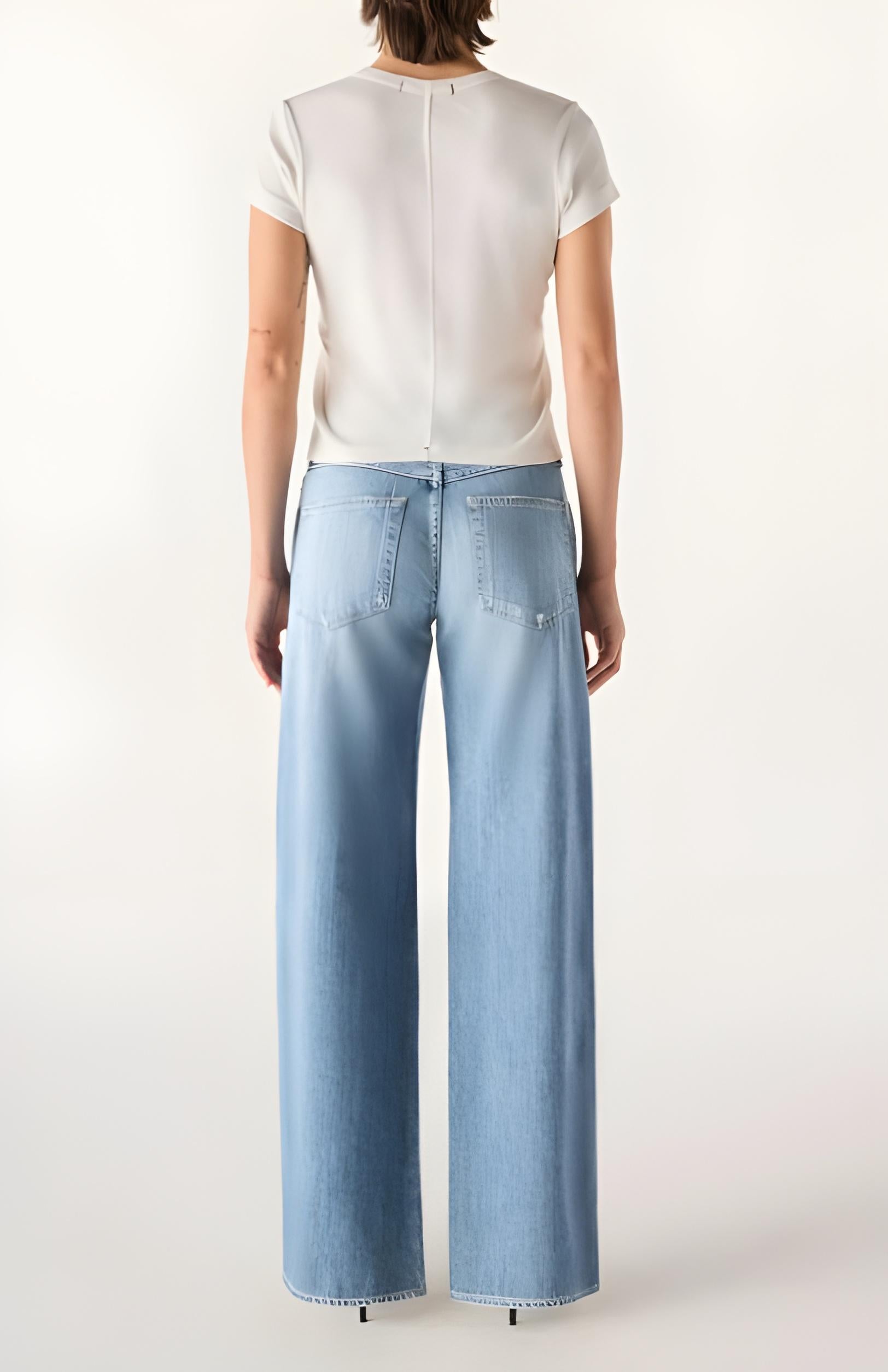 Person wearing light blue jeans and a white top on a white background
