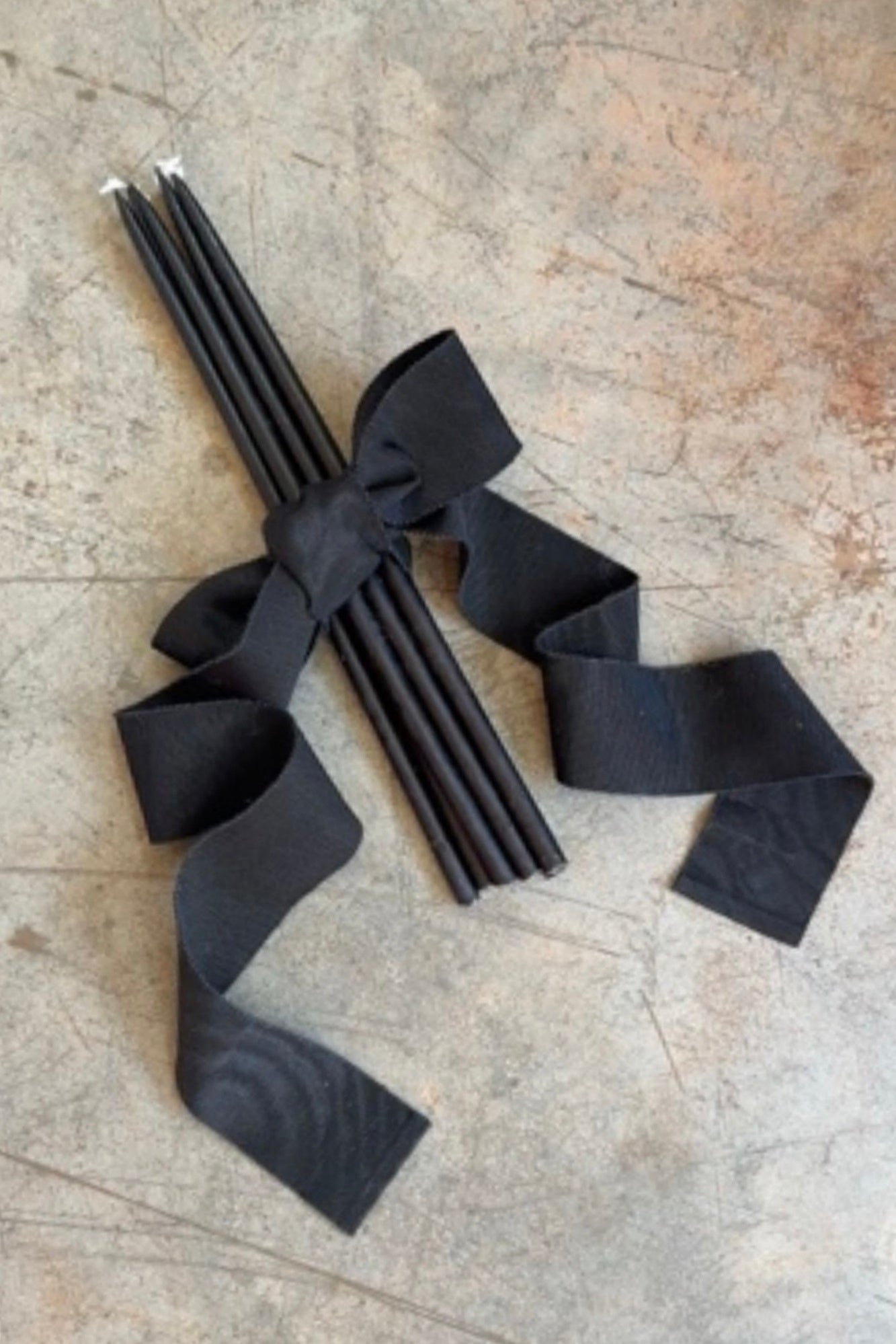 Black ribbons tied around a bundle of sticks on a textured surface