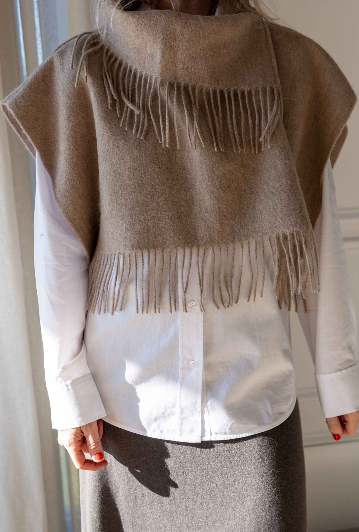 Close-up of the by Malene Birger Turtla in Grey Brown Melange, fringed wool cape scarf worn over a white shirt