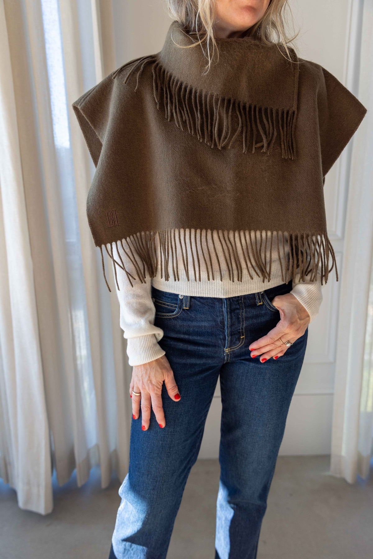 by Malene Birger Turtla in Hunt olive wool, fringed cape scarf worn over a cream knit with blue jeans
