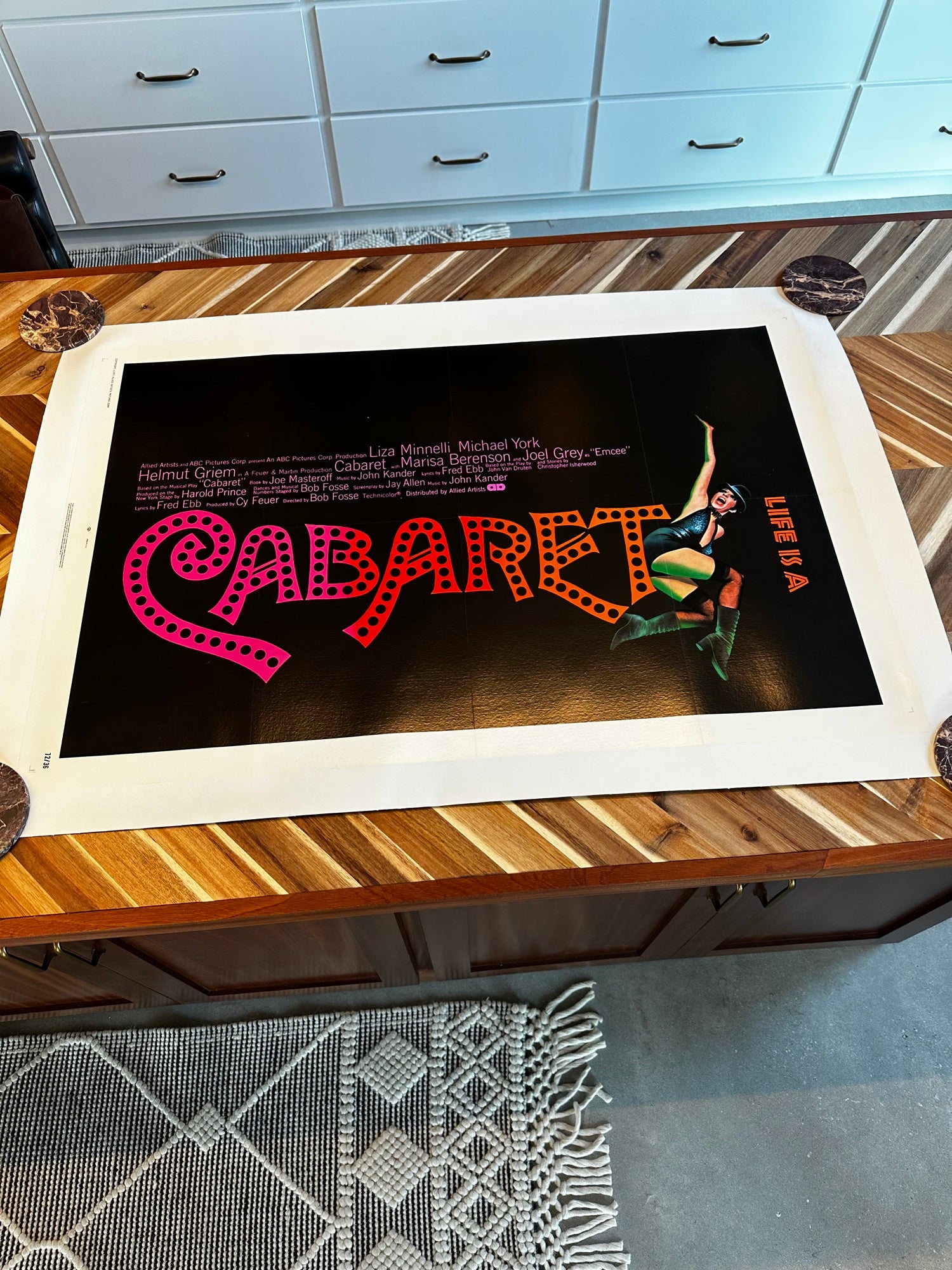 Poster of 'Cabaret' on a wooden table with a kitchen background